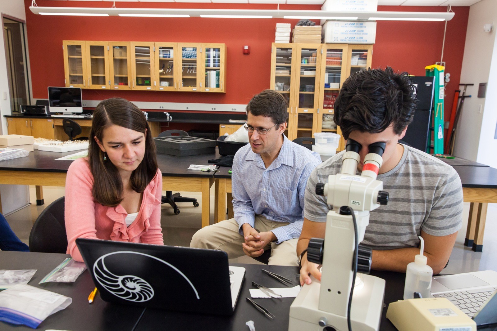 David Lubertazzi (center) helps Geanina Fripp and Scott Summers identify ant specimens that the students collected in Haiti.