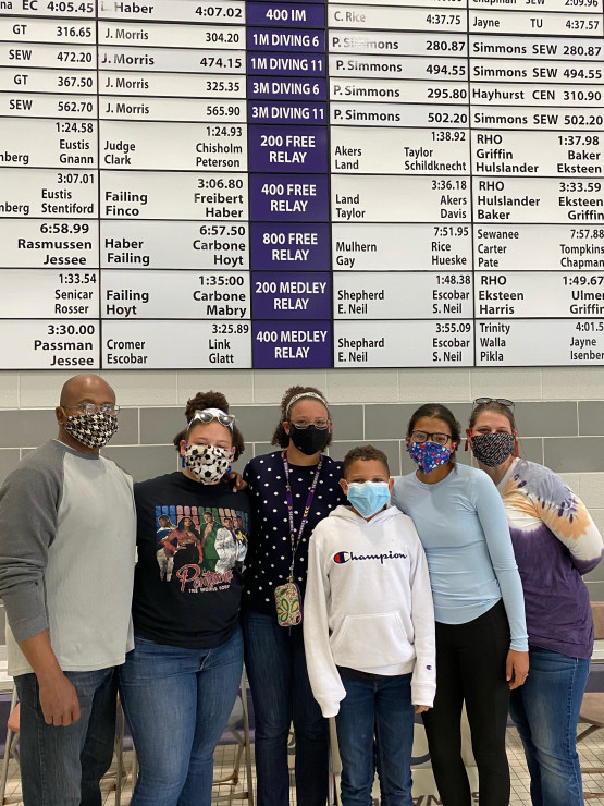 Simmons' family in front of the record board at the Fowler Center Natatorium. Simmons notes this was the first time they'd been able to see the board in person, after the COVID-19 pandemic limited campus visits and athletic events.