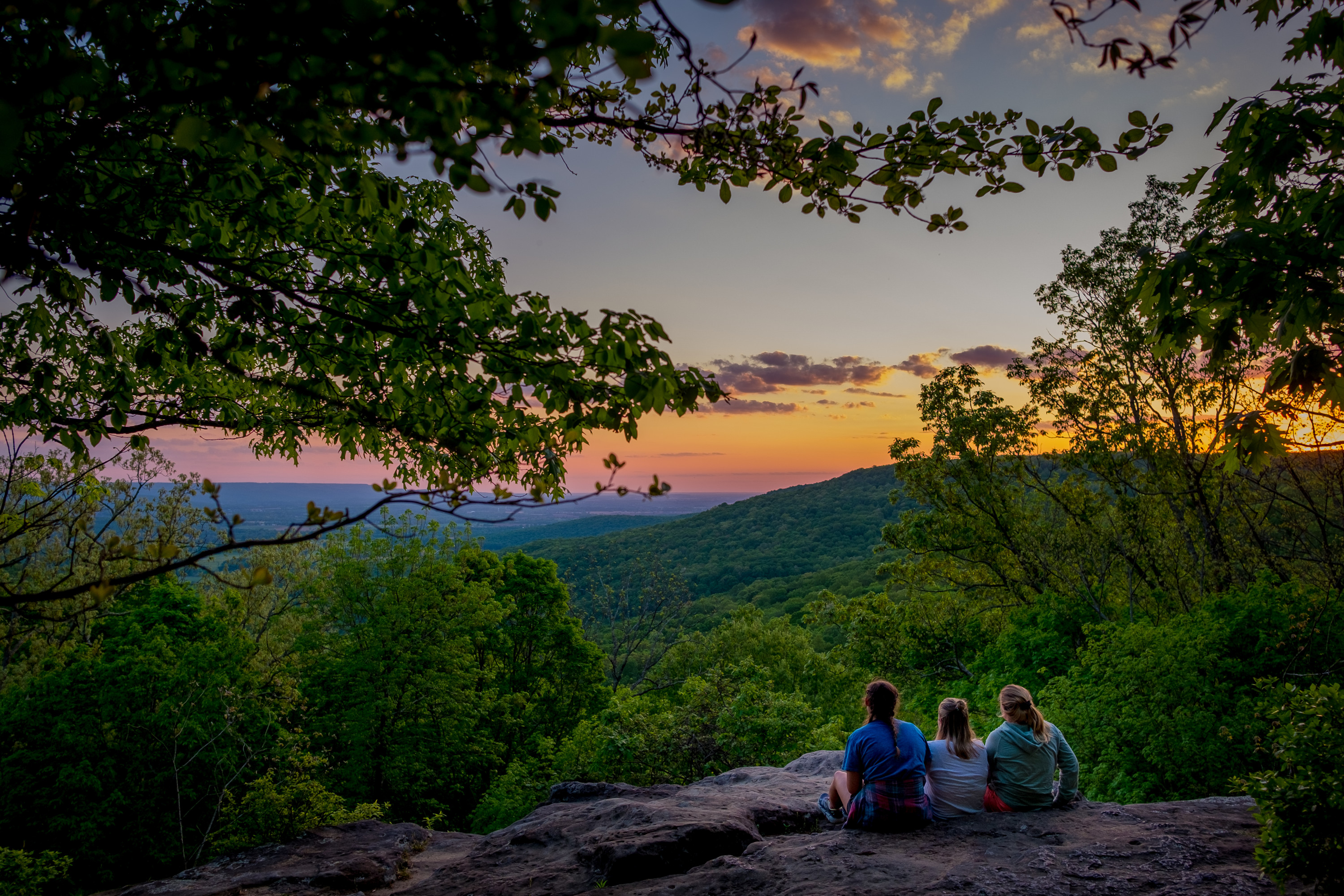 Three students on a bluff at sunset